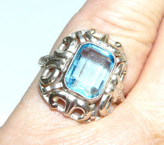achteckiges Einzelstück, floraler Vintage-Ring aus 835 Silber, poliert, eine achteckige, hellblaue, funkelnd facettierte Aquamarin-Replik, Zargenfassung mit Millesgriffes-Rand, Jugendstil-Bögen und gravierte Ringschiene, Ringweite 53, um 1930 - Goldschmiede-Danilo