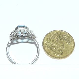 achteckiges Einzelstück, floraler Vintage-Ring aus 835 Silber, poliert, eine achteckige, hellblaue, funkelnd facettierte Aquamarin-Replik, Zargenfassung mit Millesgriffes-Rand, Jugendstil-Bögen und gravierte Ringschiene, Ringweite 53, um 1930 - Goldschmiede-Danilo