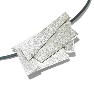 Handarbeit wandelbarer Unikat-Anhänger aus massiv 925 Silber, in variablen Positionen tragbar, ca. 32 mm x 20 mm, 4 verdeckte Schlaufen, besondere Oberflächenstruktur und polierten Kanten, in mehreren Ebenen geometrische Flächen verbunden, dreidimensional. Dazu paßt - Unikatschmuck nur erhältlich im Onlineshop von Juwelier & Goldschmiede Danilo! 