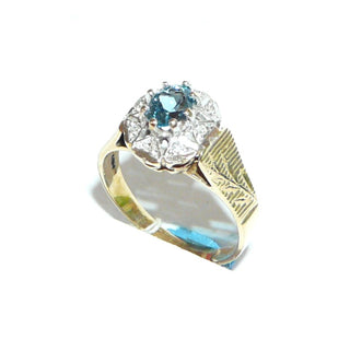 ovales Einzelstück, Blautopasring aus 375 Gold, eine ovale Rosette aus 8 Herzen mit je einem Diamant im Pavé gefaßt, in den Tiefen rhodiniert, ein ovaler, facettierter, aquamarin-hellblauer Edeltopas mit 8 Krappen gehalten, floral gravierte Seitenflächen / Seitenteile & poliert, Ringweite 57 - Goldschmiede Danilo