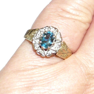 ovales Einzelstück, Blautopasring aus 375 Gold, eine ovale Rosette aus 8 Herzen mit je einem Diamant im Pavé gefaßt, in den Tiefen rhodiniert, ein ovaler, facettierter, aquamarin-hellblauer Edeltopas mit 8 Krappen gehalten, floral gravierte Seitenflächen / Seitenteile & poliert, Ringweite 57 - Goldschmiede Danilo