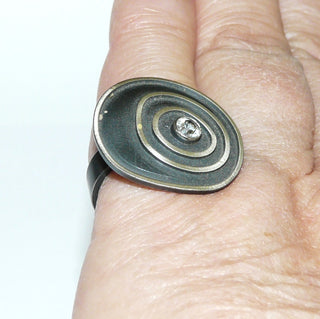 Einzelstück, Lorena-Design, schwarzer Ring "Konzentrik groß" aus 925 Silber, mit einem runden, funkelnd facettierten Bergkristall, seidenmatt, in den Tiefen geschwärzt, asymmetrische konzentrische Kreise, Ringweite 53,5. Österreichischer Design-Schmuck -	
Nur erhältlich im Onlineshop von Juwelier & Goldschmiede Danilo!
