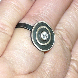 Einzelstück, Lorena-Design, schwarzer Ring "Konzentrik klein" aus 925 Silber, mit einem Bergkristall, seidenmatt, in den Tiefen geschwärzt, asymmetrische konzentrische Kreise, Ringweite 55,5. Österreichischer Design-Schmuck. -	Unikate und Pretiosen nur erhältlich im Onlineshop der Goldschmiede Danilo!