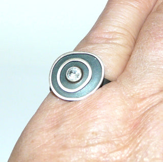 Einzelstück, Lorena-Design, schwarzer Ring "Konzentrik klein" aus 925 Silber, mit einem Bergkristall, seidenmatt, in den Tiefen geschwärzt, asymmetrische konzentrische Kreise, Ringweite 55,5. Österreichischer Design-Schmuck. -	Unikate und Pretiosen nur erhältlich im Onlineshop der Goldschmiede Danilo!