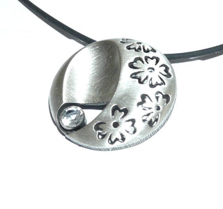 Einzelstück, Nordform-Design, großer runder Anhänger "Blumenwiese" aus 925 Silber mit einem runden, funkelnd facettierten Bergkristall, seidenmatt, in den Tiefen geschwärzt. Zum Durchfädeln. Anlaufgeschützt. Die gesamte skandinavische / finnische Nordform-Kollektion ist so designt, daß fast alle Schmuckstücke miteinander kombinierbar sind. Besonders gut zu diesem Schmuckstück paßt Ring Nord 0042 + den Ohrringen Nord 0064. (Lieferung erfolgt ohne Kette) -	Finnlandschmuck bei Goldschmiede Danilo