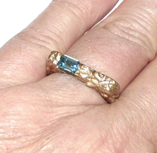 besonderes Einzelstück, handgefertigter Unikat-Blautopasring mit quadratischer Außenform, zerklüftete Oberfläche in massiv 333 Gold, ein funkelnd facettierter, dunkel aquamarinblauer Topas im Baguette-Schliff, von 2 Seiten gefaßt, eine Seitenfläche glatt & poliert, Ringweite 58 - Goldschmiede Danilo