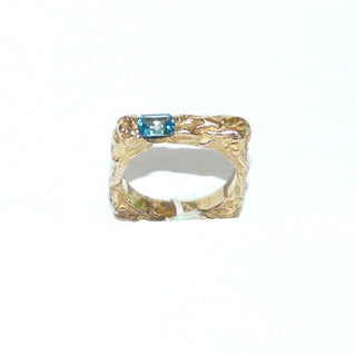 besonderes Einzelstück, handgefertigter Unikat-Blautopasring mit quadratischer Außenform, zerklüftete Oberfläche in massiv 333 Gold, ein funkelnd facettierter, dunkel aquamarinblauer Topas im Baguette-Schliff, von 2 Seiten gefaßt, eine Seitenfläche glatt & poliert, Ringweite 58 - Goldschmiede Danilo