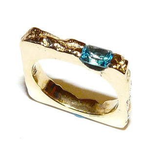 besonderes Einzelstück, handgefertigter Unikat-Blautopasring mit quadratischer Außenform, zerklüftete Oberfläche in massiv 333 Gold, ein funkelnd facettierter, dunkel aquamarinblauer Topas im Baguette-Schliff, von 2 Seiten gefaßt, eine Seitenfläche glatt & poliert, Ringweite 58 - Goldschmiede Danilo