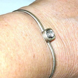 Einzelstück, Vintage-Armreif, Armspange aus 925 Silber mit einem runden, funkelnd facettierten Bergkristall, sicher in einer Krappenfassung in einem abgerundeten Quadrat eingefaßt, seidenmatt, Innenumfang 17 cm, Einhakverschluß am Stein, um 1970 - -	Vintage-Schmuck nur im Onlineshop von danilogold!