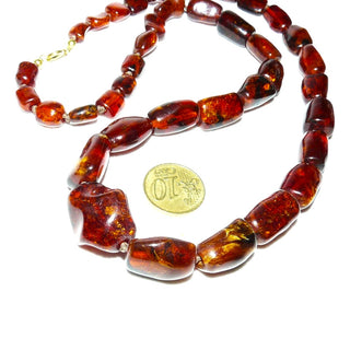 antikes Einzelstück, handgearbeitete Vintage-Bernstein-Kette aus polierten größeren Tönnchen im Verlauf mit einem Mittelstein, durchgeknotet, dunkleres Rotbraun mit schönen Einschlüssen, Verschluß aus Gold-Doublé, Gesamtlänge 60 cm, um 1950 -	Unikatschmuck nur erhältlich im Onlineshop von Juwelier & Goldschmiede Danilo! 