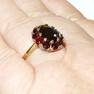 Vintage-Einzelstück, Granatring aus 333 Gold mit einem größeren ovalen & 10 kleineren runden, funkelnd facettierten Böhmischen Granaten in schöner Farbe im Brillantschliff, luftiges Körbchen unter der ovalen Rosette aus Krappenfassungen, Ringweite 56, um 1960 - Goldschmiede Danilo