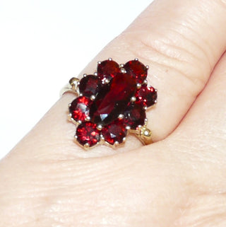 Vintage-Einzelstück, Granatring aus 333 Gold mit einem langovalen & 8 runden, funkelnd facettierten Granate in schöner Farbe, ovale Rosette in Krappenfassungen, 2 Kügelchen als Übergang zur Ringschiene, Ringweite 54,5, um 1960, Friedrich Hutte Pforzheim - Goldschmiede Danilo