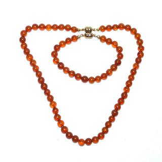 Einzelstücke, Vintage-Set, Kette (48 cm lang) + Armband (21 cm lang) aus dezent matten Bernstein-Kugeln, mittleres Cognac-orange, gleichlaufend ungeknotet aufgereiht, 2 gleiche Verschlüsse, Magnete aus Gold-Doublé, dadurch können beide Teile auch zusammen als eine lange Kette von 69 cm Länge getragen werden, um 1950  -	Vintage-Schmuck nur im Onlineshop von danilogold!