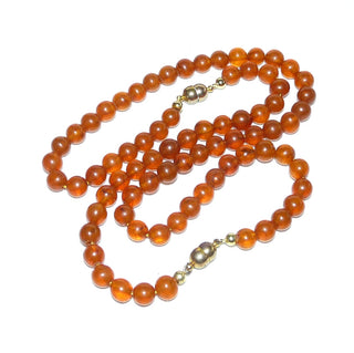 Einzelstücke, Vintage-Set, Kette (48 cm lang) + Armband (21 cm lang) aus dezent matten Bernstein-Kugeln, mittleres Cognac-orange, gleichlaufend ungeknotet aufgereiht, 2 gleiche Verschlüsse, Magnete aus Gold-Doublé, dadurch können beide Teile auch zusammen als eine lange Kette von 69 cm Länge getragen werden, um 1950  -	Vintage-Schmuck nur im Onlineshop von danilogold!