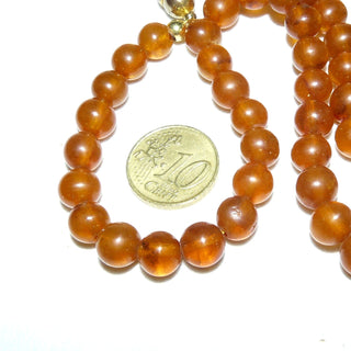 Einzelstücke, Vintage-Set, Kette (48 cm lang) + Armband (21 cm lang) aus dezent matten Bernstein-Kugeln, mittleres Cognac-orange, gleichlaufend ungeknotet aufgereiht, 2 gleiche Verschlüsse, Magnete aus Gold-Doublé, dadurch können beide Teile auch zusammen als eine lange Kette von 69 cm Länge getragen werden, um 1950  -	Vintage-Schmuck nur im Onlineshop von danilogold!