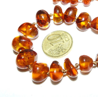 handgefädeltes Einzelstück, Bernstein-Kette aus polierten, unregelmäßigen, dicken Nuggets in Linsenform, dunkleres Cognac-braun mit schönen Einschlüssen, im Verlauf durchgeknotet, Verschluß aus Gold-Doublé, Gesamtlänge 65 cm -	Nur erhältlich im Onlineshop von Juwelier & Goldschmiede Danilo!