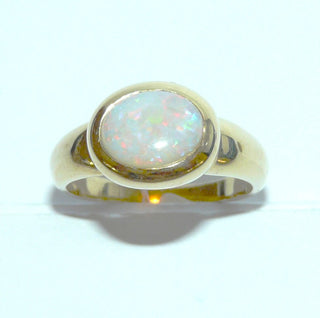 Einzelstück, breiter Ring aus massivem 585 Gelbgold mit einem weißen, kristallinen, australischen Opal-Cabochon. Das schillernde Oval ist interessant quer zum Finger eingearbeitet, der große Stein schillert herrlich in allen Farben, aber mit besonders viel Rot Der Ring ist poliert und der Stein sicher in einer breiten Zargenfassung eingefaßt, Ringweite 59 - Unikate und Pretiosen nur erhältlich im Onlineshop der Goldschmiede Danilo!