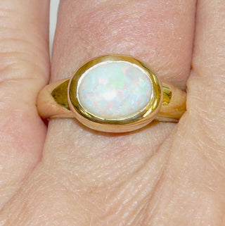 Einzelstück, breiter Ring aus massivem 585 Gelbgold mit einem weißen, kristallinen, australischen Opal-Cabochon. Das schillernde Oval ist interessant quer zum Finger eingearbeitet, der große Stein schillert herrlich in allen Farben, aber mit besonders viel Rot Der Ring ist poliert und der Stein sicher in einer breiten Zargenfassung eingefaßt, Ringweite 59 - Unikate und Pretiosen nur erhältlich im Onlineshop der Goldschmiede Danilo!