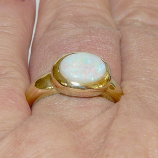 Einzelstück, breiter Ring aus massivem 585 Gelbgold mit einem weißen, kristallinen, australischen Opal-Cabochon. Das schillernde Oval ist interessant quer zum Finger eingearbeitet, der große Stein schillert herrlich in allen Farben, aber mit besonders viel Rot Der Ring ist poliert und der Stein sicher in einer breiten Zargenfassung eingefaßt, Ringweite 59 -	Unikate und Pretiosen nur erhältlich im Onlineshop der Goldschmiede Danilo!