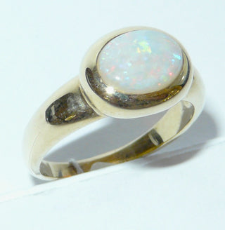 Einzelstück, breiter Ring aus massivem 585 Gelbgold mit einem weißen, kristallinen, australischen Opal-Cabochon. Das schillernde Oval ist interessant quer zum Finger eingearbeitet, der große Stein schillert herrlich in allen Farben, aber mit besonders viel Rot Der Ring ist poliert und der Stein sicher in einer breiten Zargenfassung eingefaßt, Ringweite 59 -	Unikate und Pretiosen nur erhältlich im Onlineshop der Goldschmiede Danilo!