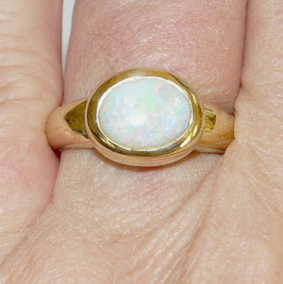 Einzelstück, breiter Ring aus massivem 585 Gelbgold mit einem weißen, kristallinen, australischen Opal-Cabochon. Das schillernde Oval ist interessant quer zum Finger eingearbeitet, der große Stein schillert herrlich in allen Farben, aber mit besonders viel Rot Der Ring ist poliert und der Stein sicher in einer breiten Zargenfassung eingefaßt, Ringweite 59 -	Unikate und Pretiosen nur erhältlich im Onlineshop der Goldschmiede Danilo!