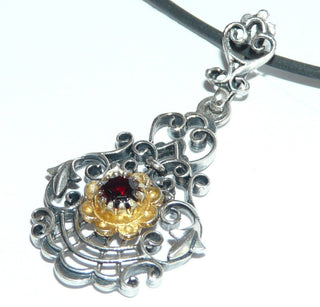 Einzelstück, filigraner, antik wirkender Granat-Anhänger aus 925 Silber, in der vergoldeten Mitte ein runder, funkelnd facettierter Granat, umrahmt von Schnörkeln + Bögen, wirkt wie feine Spitze in Metall verewigt, in den Tiefen geschwärzt. Dazu paßt Ring Ri 0147. (Lieferung erfolgt ohne Kette) -	Einzelstücke nur erhältlich bei www.danilogold-shop.de