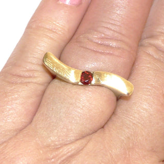 Schmales Einzelstück, geschwungener Granatring aus 333 Gold poliert mit einem runden, funkelnd facettierten Granat, von 2 Seiten gefaßt, Spannoptik, gerades Oberteil, das leicht über die Nachbarfinger reicht, Ringweite 56,5 - Goldschmiede Danilo