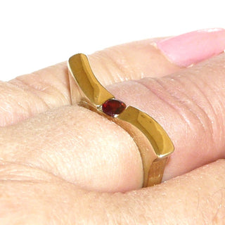 Schmales Einzelstück, geschwungener Granatring aus 333 Gold poliert mit einem runden, funkelnd facettierten Granat, von 2 Seiten gefaßt, Spannoptik, gerades Oberteil, das leicht über die Nachbarfinger reicht, Ringweite 56,5 - Goldschmiede Danilo