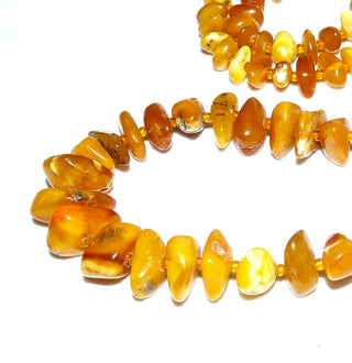 antikes Einzelstück, handgeschliffene Vintage-Bernstein-Kette aus polierten Chips / Splittern im Verlauf ungeknotet aufgereiht mit kleinen Mini-Kügelchen als Abstandshalter für einen besonders schönen Fall am Hals, hell-honigfarbener Butterscotch, ohne Verschluß, Gesamtlänge 68 cm, um 1930 -	Nur erhältlich im Onlineshop von Juwelier & Goldschmiede Danilo!
