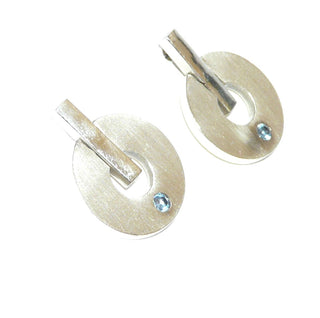 runde Einzelstücke, seidenmatte Donut-Ohrstecker, Kreise beweglich an einem polierten Stab angebracht, je ein funkelnd facettierter, hellblauer Zirkonia als Aquamarin-Replik direkt eingelassen, massiv 925 Silber - Goldschmiede Danilo