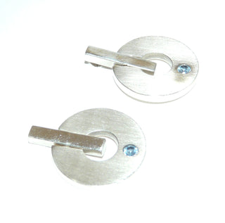 runde Einzelstücke, seidenmatte Donut-Ohrstecker, Kreise beweglich an einem polierten Stab angebracht, je ein funkelnd facettierter, hellblauer Zirkonia als Aquamarin-Replik direkt eingelassen, massiv 925 Silber - Goldschmiede Danilo