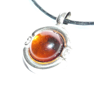 rundes Einzelstück, Vintage Bernsteinanhänger aus 835 Silber mit einem klaren natürlichen honigfarbenen Bernstein-Cabochon mit dunklem Einschluss, wulstiger Rand mit zwei Schnörkeln, Andreas Daub Pforzheim um 1960 - Goldschmiede Danilo