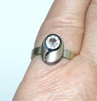 Einzelstück, Nordform-Design Ring "kleines Oval" aus 925 Silber mit einem funkelnd facettierten Bergkristall, seidenmatt, in den Tiefen geschwärzt, verstellbare Ringweite bis ca. 59. Die gesamte skandinavische / finnische Nordform-Kollektion ist so designt, daß fast alle Schmuckstücke miteinander kombinierbar sind. Besonders gut zu diesem Schmuckstück paßt Nord 0017 (Kennen Sie Ihre Ringweite? Dann geben Sie diese bei der Bestellung an, und wir stellen diese Weite vorab für Sie ein!) -	Einzelstücke nur